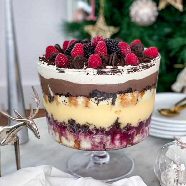 The finished trifle is on the table with plates and spoons in the background.