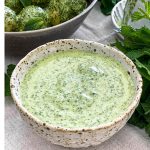 A close up of the bowl of Easy Mint Dressing. It is a lovely green colour with darker flecks of herbs throughout.