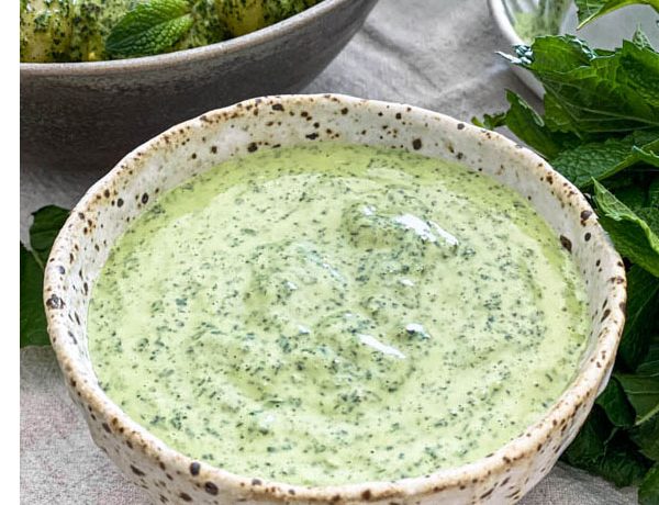 A close up of the bowl of Easy Mint Dressing. It is a lovely green colour with darker flecks of herbs throughout.