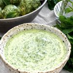 The bowl of Mint Dressing is surrounded by mint and in the background is a bowl of Potato Salad made with the dressing.