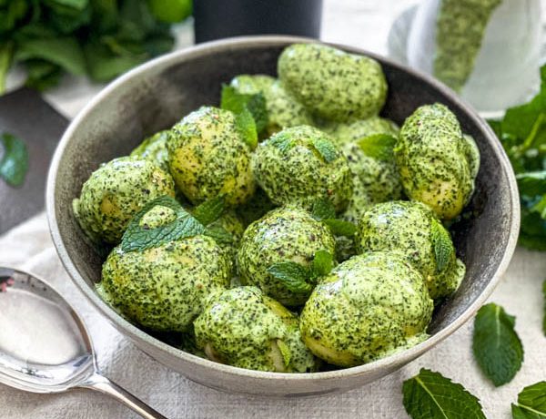 The New Potato Salad with Mint Dressing is in a bowl on a table with a jug of the Mint Dressing in the background.