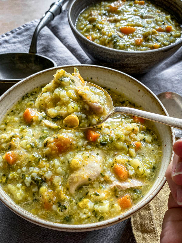 A close up of the soup with a spoonful of soup in the foreground.