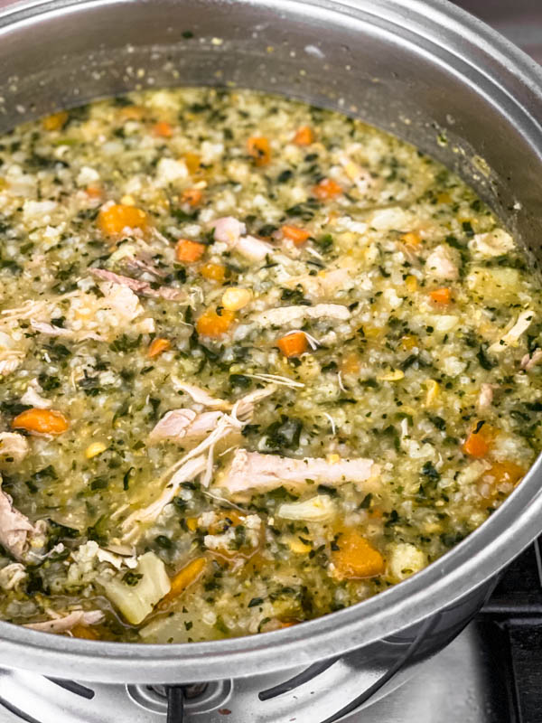 A close up of the soup in the pot. You can see all the vegetables, rice and chicken.