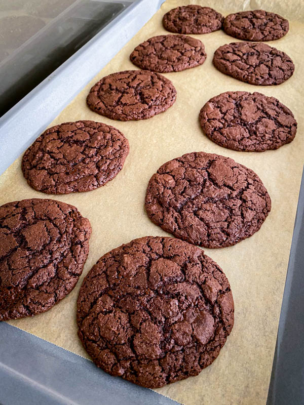 The baked cookies are out of the oven and resting on the oven tray until cooled.