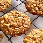 A close up of the Chewy Anzac Biscuits resting on a vintage black wire cooling rack.