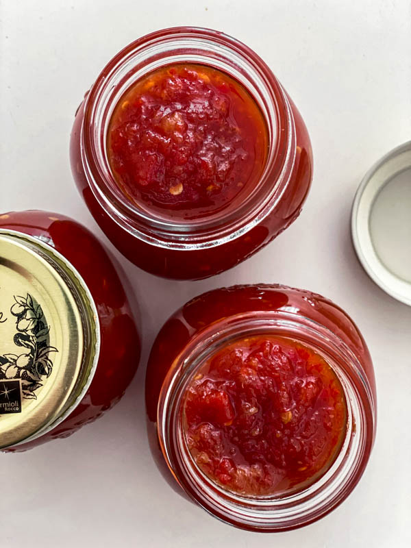 Looking down into the filled jars of Tomato Chilli Jam before the lids are screwed on.