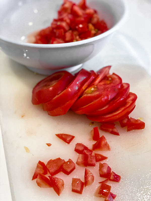 The tomatoes are being chopped into small 1/2 to 1cm cubes.