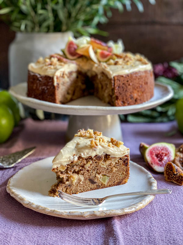 A slice of the cake is on a serving plate with the rest of the cake in the background.