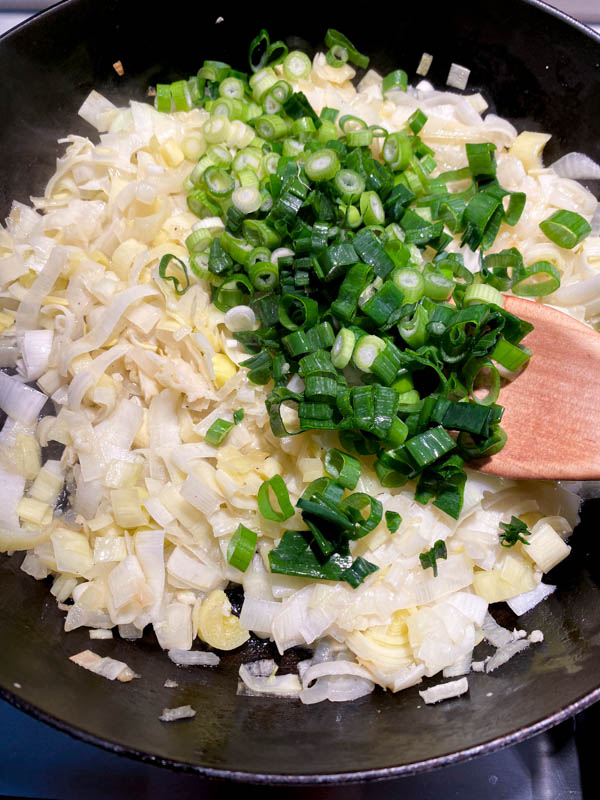Half of the spring onions have now been added to the frying pan with the cooked onions and leeks.