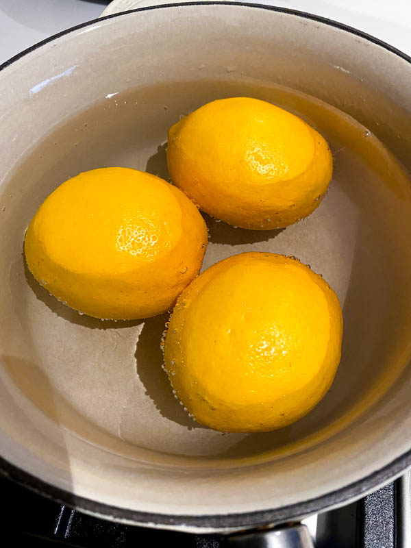 The three Meyer lemons are in a pot and covered with water ready to be boiled.