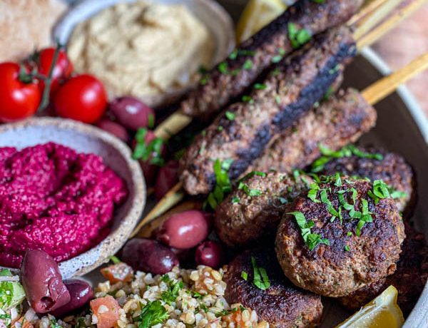 A close-up of the kofta skewers and patties with some parsley sprinkled over the top.