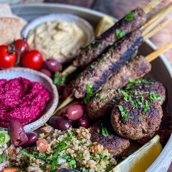 A close-up of the kofta skewers and patties with some parsley sprinkled over the top.