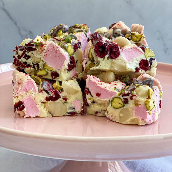 A close up of the rocky road pieces on a pink cake stand.