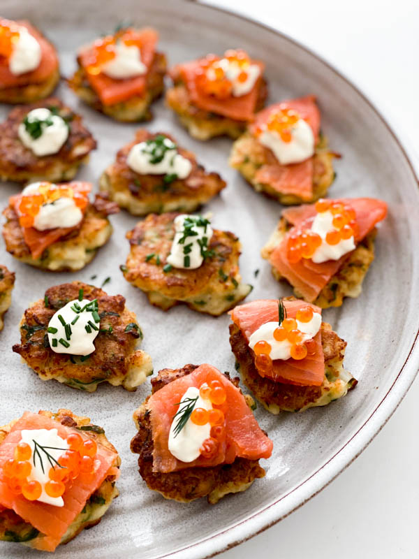 A close up of the Cauliflower Fritters on a platter with toppings, ready to be served.