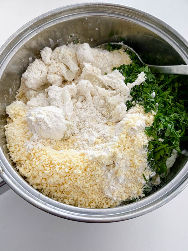 The grated parmesan, parsley and flour have been added to the cooked cauliflower in the pot.