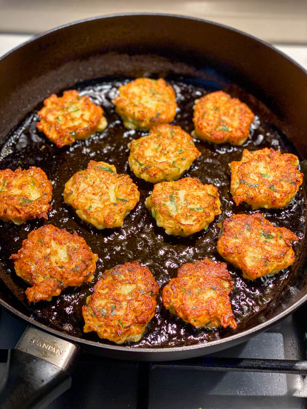 The golden fritters are now cooking on the other side in a frying pan.