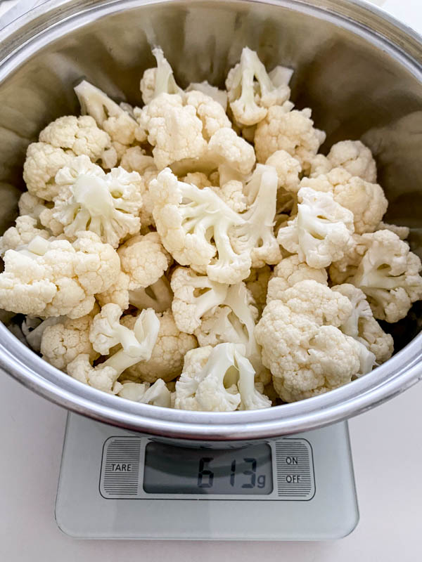 The cauliflower florets are in a bowl and weighed to get approximately 600g.