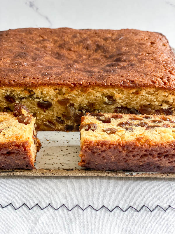 The Sultana Cake is cut showing the inside of the cake which is moist and dotted with plump sultanas.