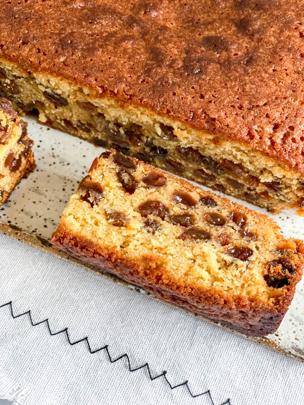 Looking down onto the cut cake showing the colour and texture of the crumb. It is moist and studded with sultanas.