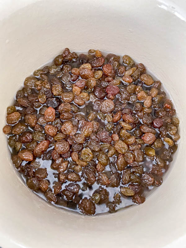 The sultanas are in a pot with water ready to be boiled.