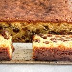 The sliced cake is on a serving plate. It is moist and filled with sultanas.