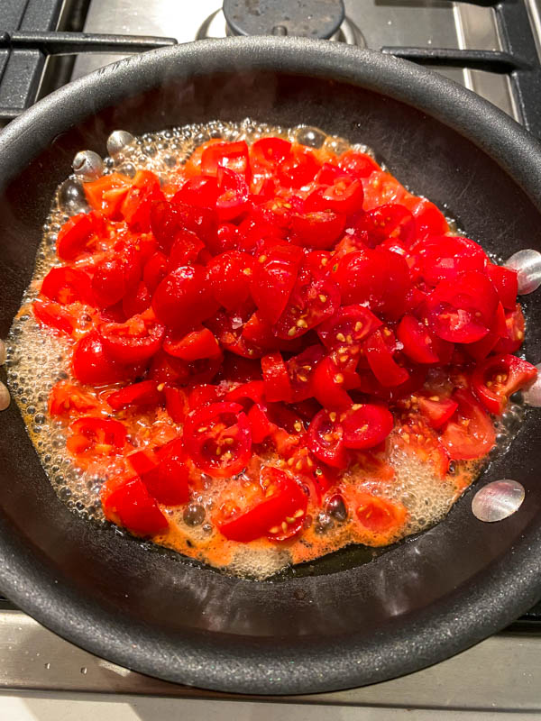 The chopped tomatoes are added to a pan with butter and olive oil.