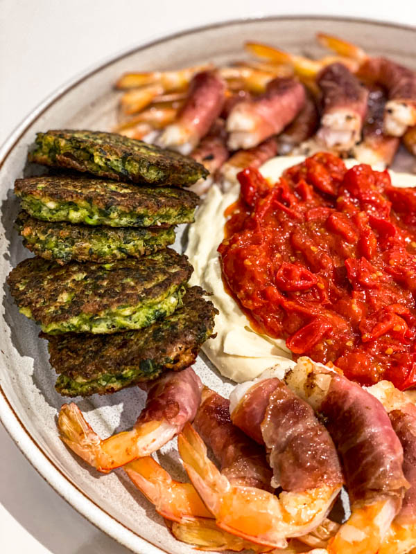 A platter of nibbles with some whipped feta in the middle. On top of the whipped feta is some Breakfast Tomato sauce. This is served with green vegetable fritters and prawns as a starter.