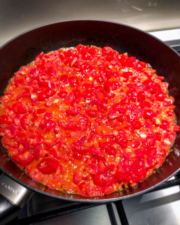 The tomatoes are simmering away in a frying pan.