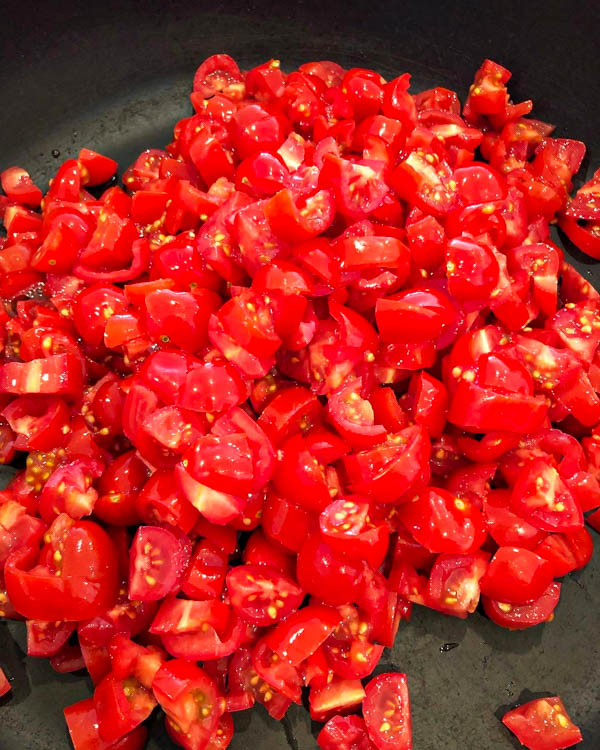 The baby roma tomatoes are quartered and ready to be cooked.