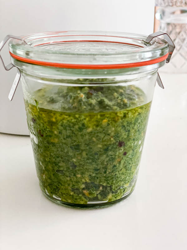 The pesto is in a jar with a thin layer of olive oil over the top. It is then sealed and will be placed in the refrigerator.