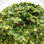 The pesto is in a bowl. It is green and vibrant with flecks of chilli and nuts throughout.
