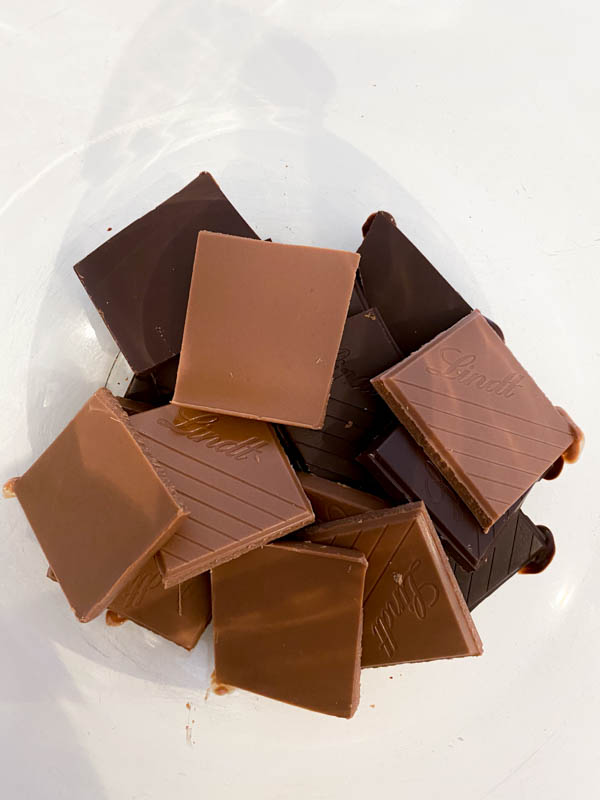 The pieces of dark and milk chocolate are in a bowl ready to be melted.