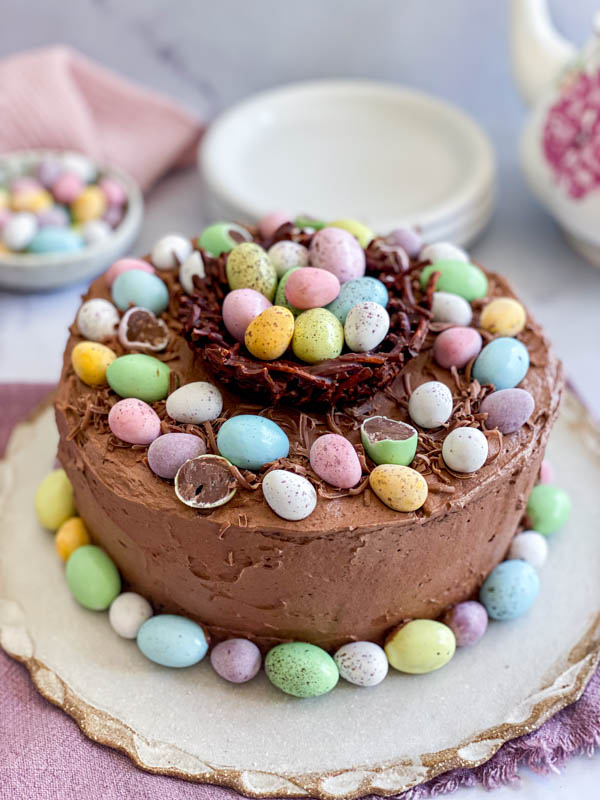 This shows the chocolate nest as a centrepiece at the top of a Chocolate Cake. It is filled with mini Easter eggs and has other mini easter eggs around it.