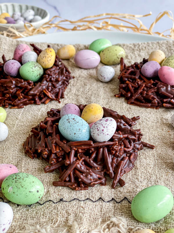 The nests are filled with mini chocolate easter eggs with a few eggs also scattered around them.