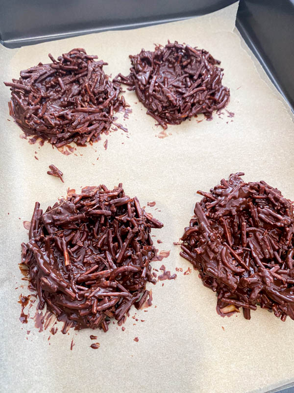 The chocolate nests have been shaped into nests and are on a baking tray that has been lined with baking paper. They will now be placed into the fridge to set.