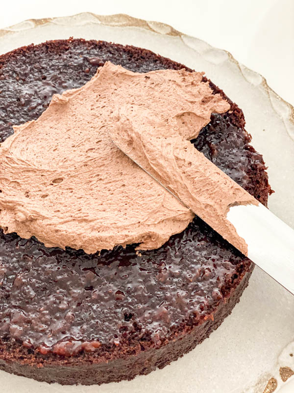 A thin layer of chocolate frosting is now added on top of the strawberry jam.