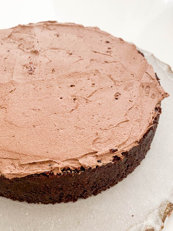 This shows the finished first layer of chocolate buttercream frosting, ready for the second layer of cake.