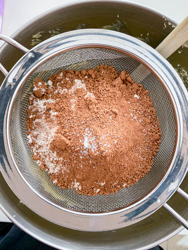The dry ingredients are in a sifter directly over the bowl with the creamed butter mixture.