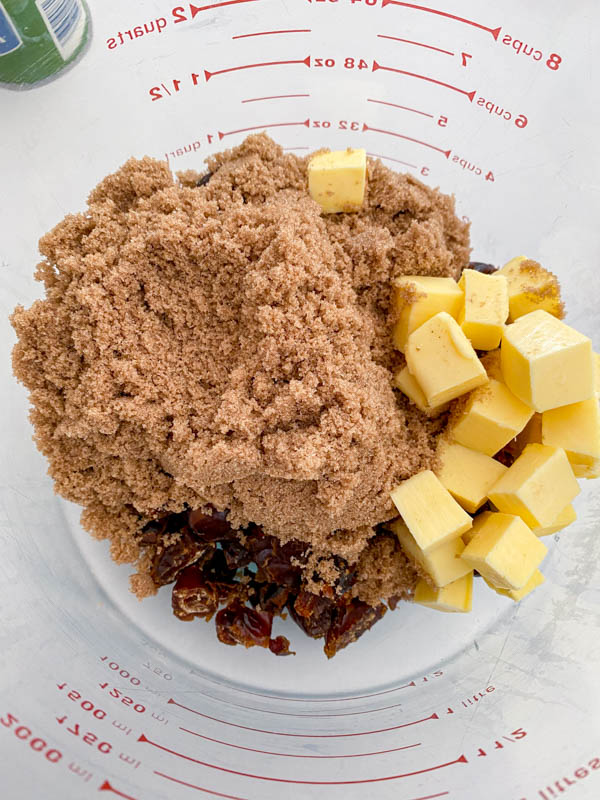 The chopped dates, brown sugar and cubes of butter are all added to a large mixing bowl.