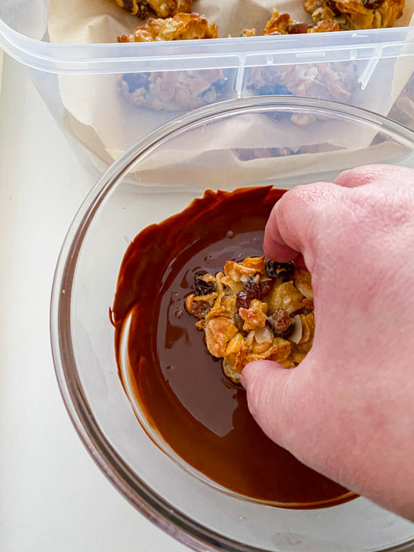 One of the florentines is now dunked into the melted chocolate just enough to cover the underside of the biscuit, before being lifted out and turned over to dry.