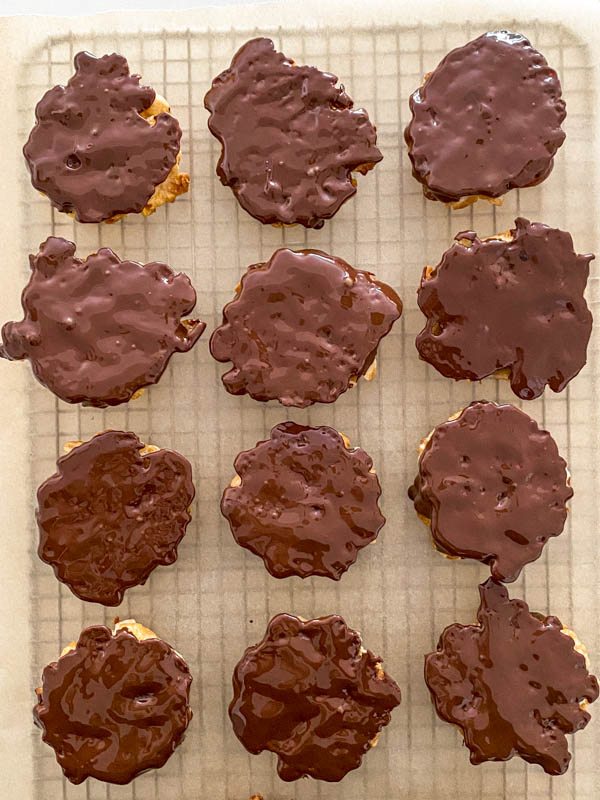 All the florentines have now been dunked in chocolate to cover the base side only. They are shown here resting chocolate side up on a wire rack that is lined with baking paper.