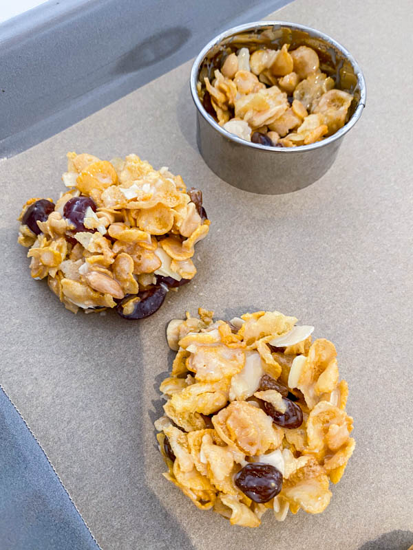 Tablespoons of the cornflakes mixture are placed into a 7cm pastry ring on a baking paper lined oven tray. The mixture is gently pressed into the mould to form a round biscuit shape.