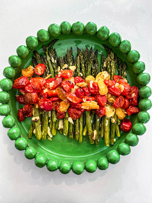 Looking down onto a green platter with the Roasted Asparagus and Tomato Salad on it.