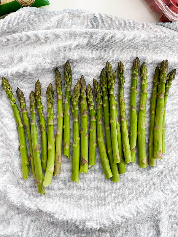 The asparagus has been washed and is laid out on a clean tea towel to dry.