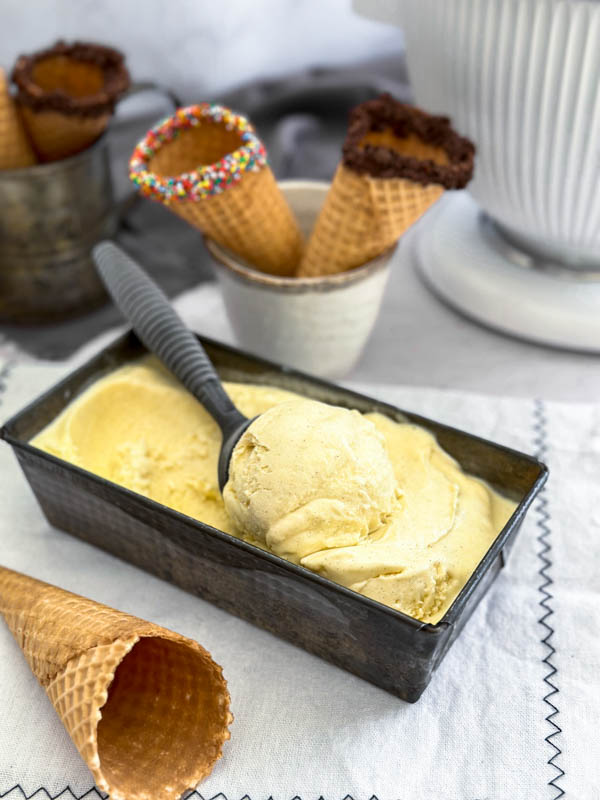 A close up of the Vanilla Bean Ice Cream with cones in the background and foreground.