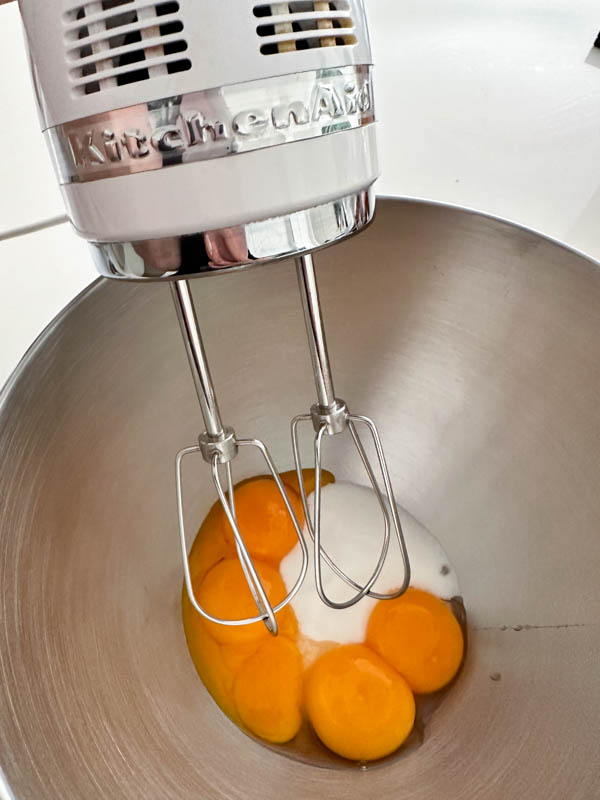 The egg yolks and sugar are in a bowl ready to be beaten with a hand held mixer.