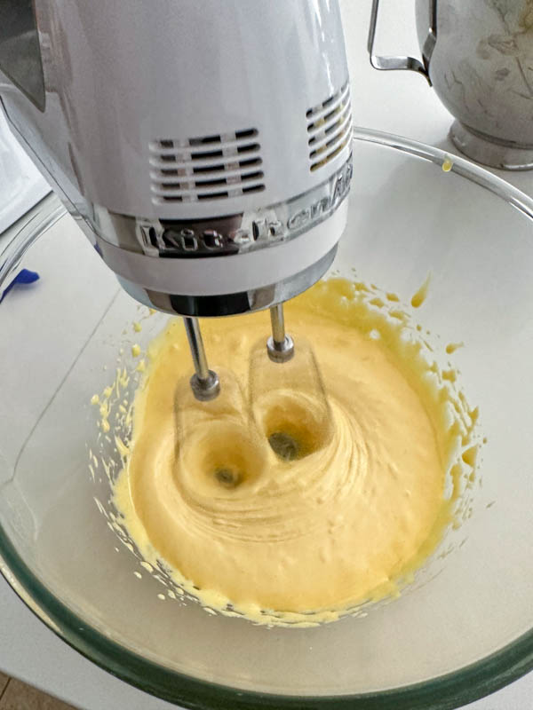 The egg yolks and sugar are being beaten together and becoming thicker and lighter in colour.